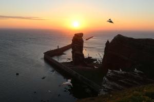 a statue of a person standing on a cliff near the ocean at Gaestehaus Cap Hoorn in Helgoland