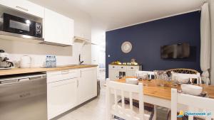 een keuken met witte kasten en een houten tafel bij Apartamenty Trio in Dziwnówek