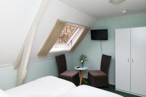 Anderen的住宿－德和勃艮萬安得潤酒店，一间卧室设有窗户、两把椅子和一张桌子