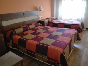 Castañares de Rioja的住宿－老闆旅館，酒店客房设有两张床和窗户。