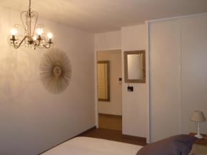 アヌシーにあるLe janua - Accortのベッド1台、シャンデリア、ドアが備わる客室です。