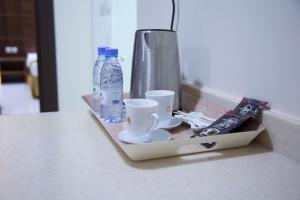a tray with cups and a bottle of water on a counter at شقق الحرير للشقق المخدومة الإقتصادية in Hafr Al-Batin