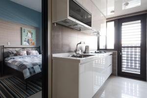 a small kitchen with a sink and a bed at LiveGRACE Apartment Xindian in Xindian
