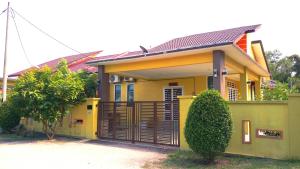 a yellow house with a gate in front of it at Amera Homestay in Cukai