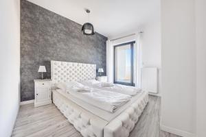 a white bedroom with a large bed with a large headboard at Prywatne apartamenty Sun & Snow w Baltic Park Molo in Świnoujście