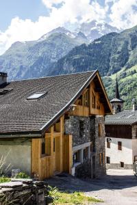 une grange avec des montagnes en arrière-plan dans l'établissement Le Rocher, à Sainte-Foy-Tarentaise