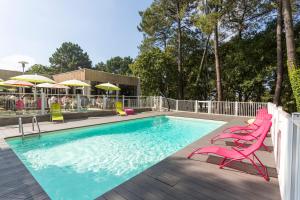 a swimming pool with pink chairs and umbrellas on a deck at ibis Lorient Centre Hôtelier in Caudan