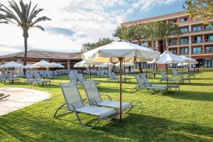 a group of chairs and an umbrella in the grass at Hipotels Hipocampo Palace & Spa in Cala Millor