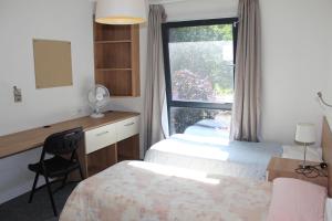 a bedroom with two beds and a desk and a window at Newington Court (Stoke Newington) in London