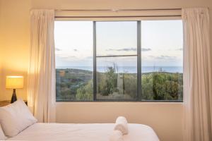 a bedroom with a bed and a large window at Kilifi Beach House in Gnarabup