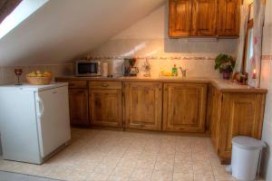 eine Küche mit Holzschränken und einem weißen Kühlschrank in der Unterkunft Apartman Maryla in Ratkovica