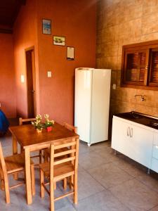 a kitchen with a table and a white refrigerator at Luz da Lua Cabanas Comfort in Praia do Rosa