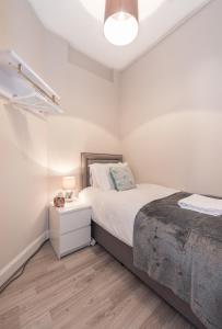 a white bedroom with a bed and a night stand at The New Westfield in Edinburgh