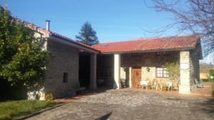kamienny dom z czerwonym dachem i patio w obiekcie Posada Paz w mieście Hinojedo