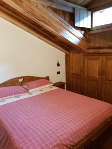 プレ・サン・ディディエにあるLa mansarda delle marmotteのベッドルーム1室(ピンクの毛布付きのベッド1台付)