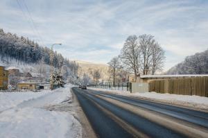 a snow covered road with a car driving down it at Penzion SPORTINO in Svoboda nad Úpou