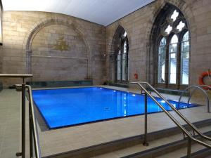 a large swimming pool with blue water in a building at Abbey Garden at the Highland Club in Fort Augustus