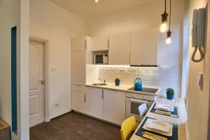 una cucina con armadi bianchi e tavolo con sedie di K29 Apartment | Budapest a Budapest