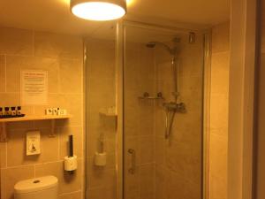 La salle de bains est pourvue d'une douche avec une porte en verre. dans l'établissement Findon Rest Ltd, à Worthing