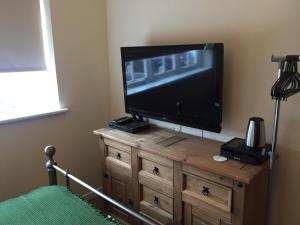 un televisor en la parte superior de un tocador en un dormitorio en Findon Rest Ltd en Worthing