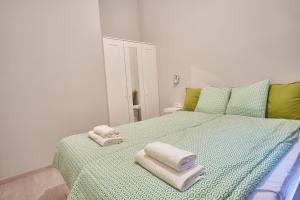 een slaapkamer met een groen bed en handdoeken bij HILD-2 Apartments | Budapest in Boedapest