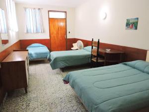 a bedroom with two beds and a table and a desk at Park Hotel in Port-au-Prince