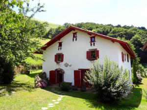 サン・テティエンヌ・ド・バイゴリにあるChambres d'hôtes Idiartekobordaの赤いシャッター付きの窓と木々のある白い家