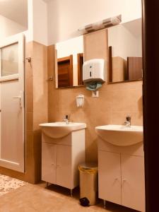un baño con 2 lavabos y un dispensador en la pared en Monte Carlo Palace Rooms, en Bucarest