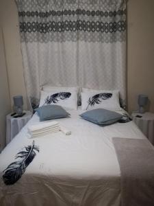 Una cama con sábanas blancas y almohadas azules. en MulMas Guest House, en Pretoria