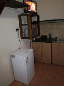cocina con nevera y TV en la pared en MulMas Guest House, en Pretoria