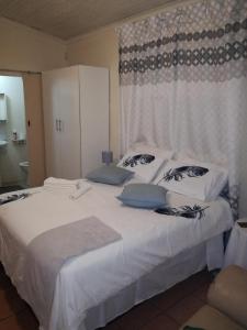 1 dormitorio con 1 cama con sábanas y almohadas blancas en MulMas Guest House, en Pretoria