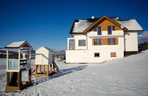a house in the snow with a playground at Agroturystyka Słoszówka in Duszniki Zdrój