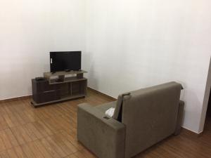 a living room with a couch and a flat screen tv at Residencial Sibaúma in Pipa
