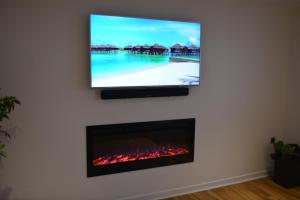 a flat screen tv hanging on a wall with a fireplace at Matysiak Apartment in Edinburgh