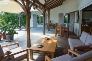 - une terrasse couverte dotée d'un mobilier en bois et d'une table dans l'établissement Villa Tiarés, à Saint-François