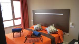 プエルト・デル・ロサリオにある2V LUXURY APARTMENT NEAR BEACHのベッドルーム1室(オレンジ色のベッド1台、椅子2脚付)