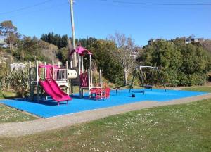 a playground with three slides and a swing set at Noah's Boutique Accommodation Moeraki in Moeraki