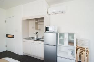 a kitchen with a refrigerator and a microwave at ETAVIA Yufuinekimae in Yufuin