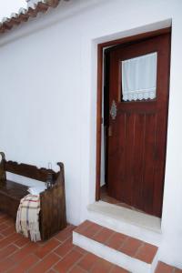 a wooden door in a white room with a bench at Casas do Palheiro Velho in Castro Marim
