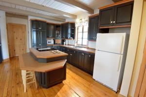 a kitchen with black cabinets and a white refrigerator at Le Champ Perché in La Malbaie