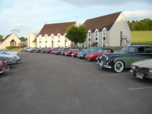 Une rangée de voitures garées sur un parking dans l'établissement Auberge De Bourgogne, à Tonnerre