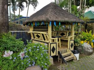 a wooden gazebo with a bench in a garden at Riverview Resort and Conference Center in Calamba