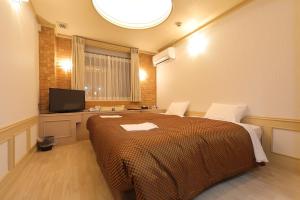 una camera con un grande letto e una televisione di Reco Hotel Mikuni a Toyonaka