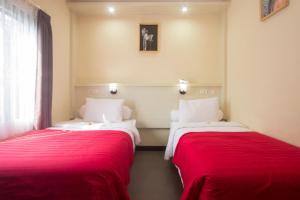 2 camas en una habitación con sábanas rojas y blancas en Maxi Hotel Kedonganan en Jimbaran