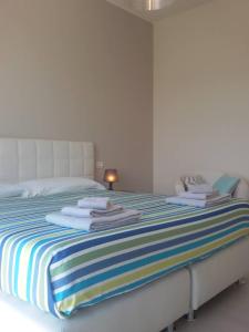 biała sypialnia z łóżkiem i ręcznikami w obiekcie Il colore dei sogni w mieście Due Carrare
