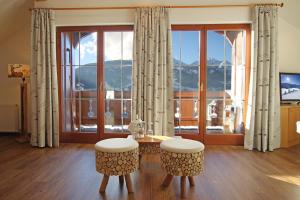 ein Wohnzimmer mit einem Tisch und Stühlen sowie einem großen Fenster in der Unterkunft Appartementhotel Zugspitzhof in Ehrwald