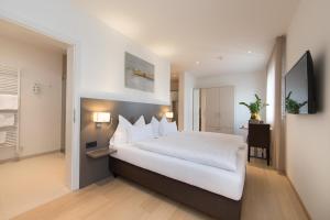 a bedroom with a large white bed and a television at Vitus Steyr Hotel & SPA Suites in Steyr
