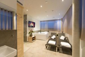 ein Badezimmer mit einer Badewanne, einem Waschbecken und einer Badewanne in der Unterkunft Vitus Steyr Hotel & SPA Suites in Steyr