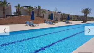 a swimming pool with chairs and umbrellas in a resort at Chalet at Little Venice - Ain Sokhna in Ain Sokhna