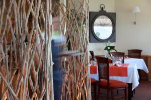 a person walking through a dining room with a wall of branches at Hôtel Panorama in Munster